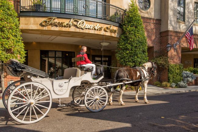 An exterior view of the French Quarter Inn with horse-drawn carriage